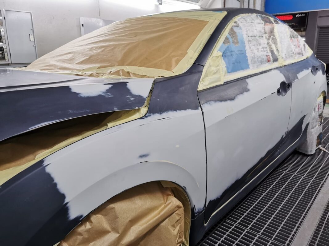 Non-painted surfaces masked on the Honda Civic before the spray booth.