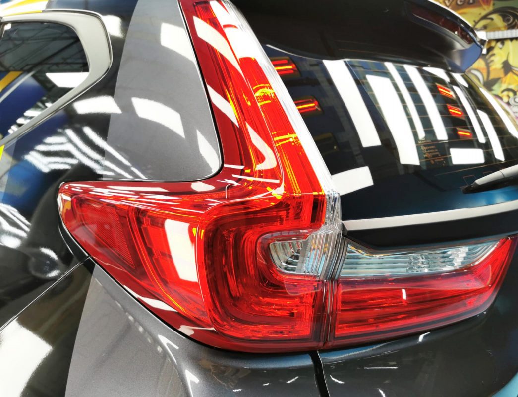 Coated bonnet of the Honda CR-V under workshop lighting.