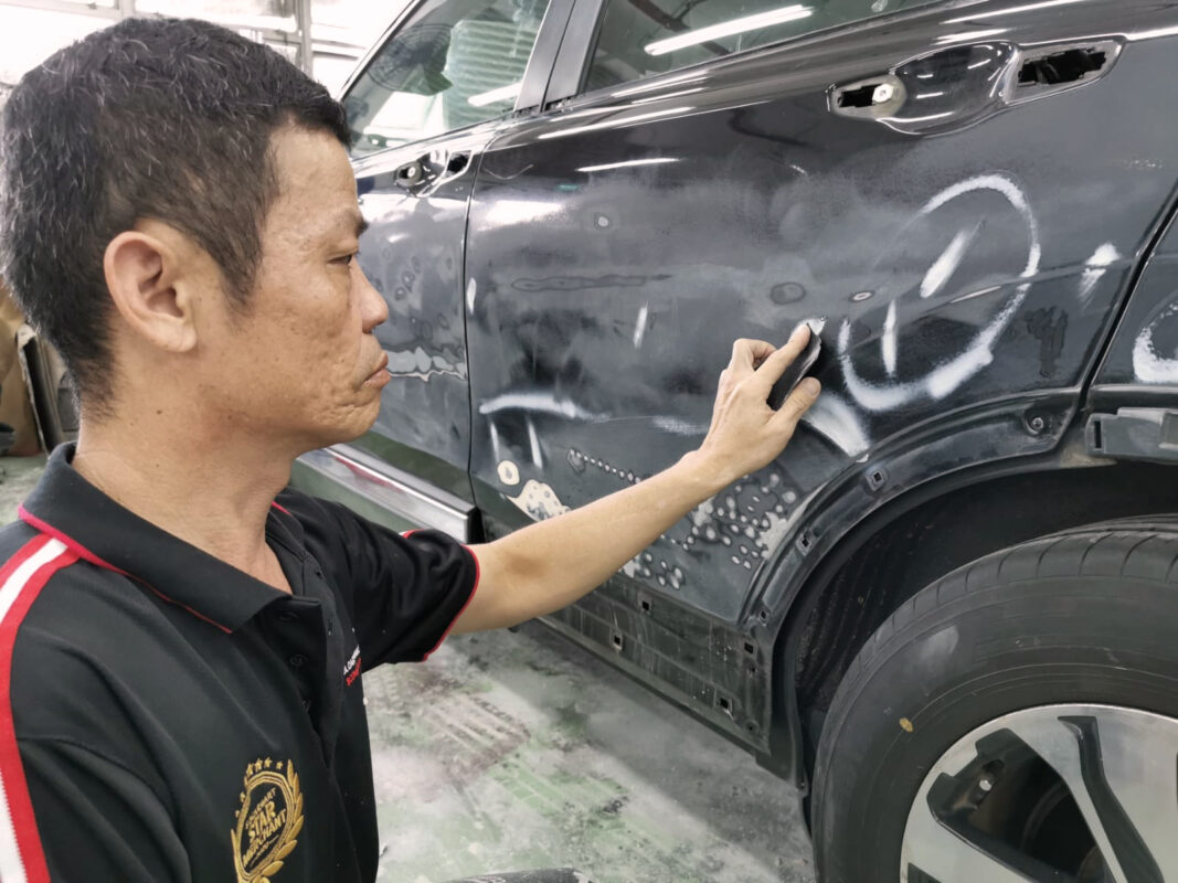 Revol Carz technician inspecting the Honda CR-V panels for dents and scratches.
