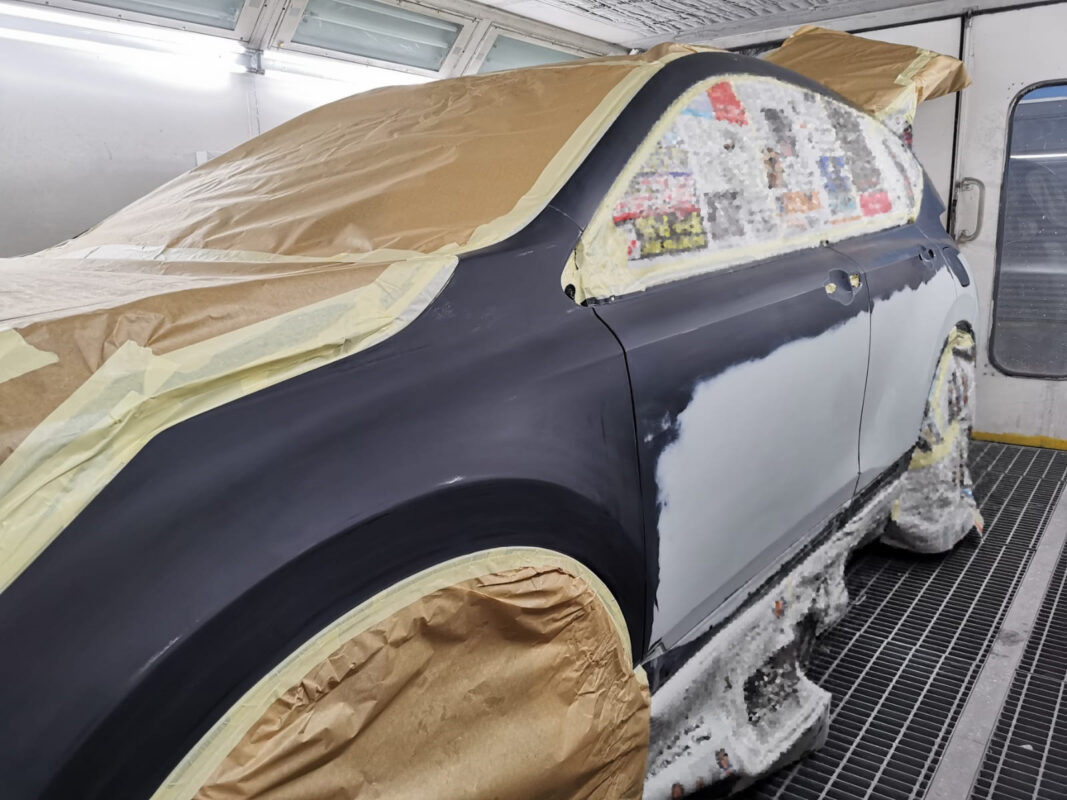 Technician masking non-painted surfaces on the Honda CR-V before the spray booth.