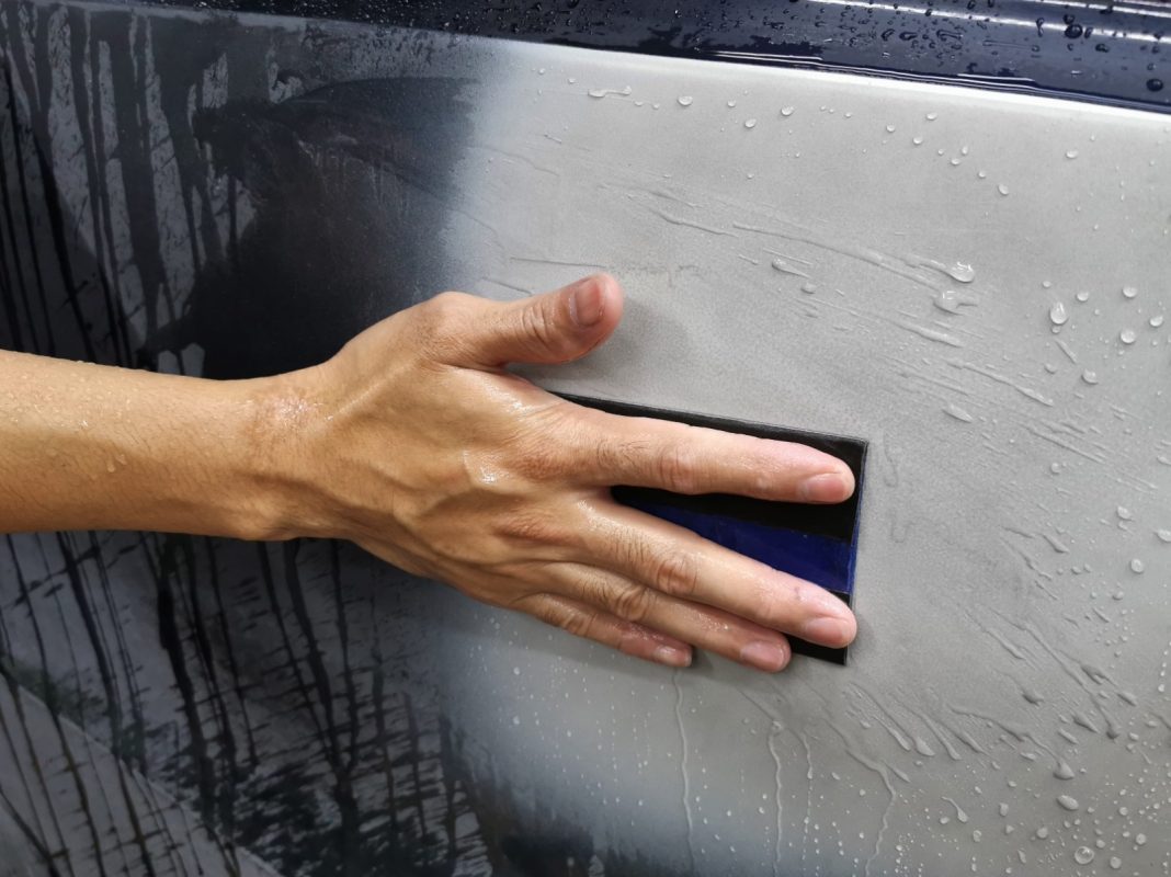Wet-sanding the Fit's panels to smooth the existing paintwork.