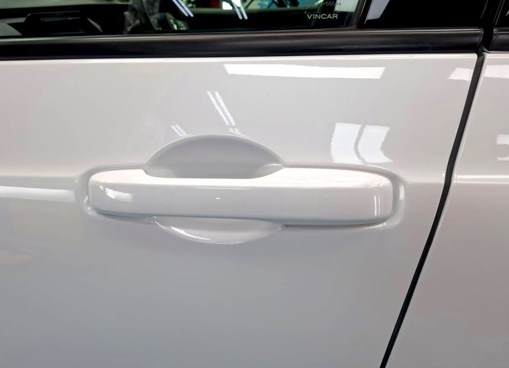 White door handle and door panel with soft reflections.