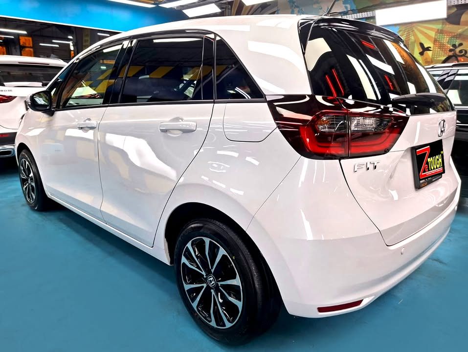 White Honda Fit, rear three-quarter view, in the workshop.