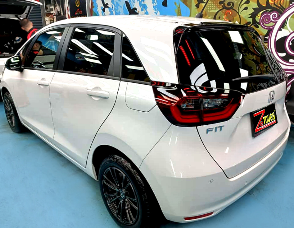 The coated bonnet of the Honda Fit under workshop lighting.