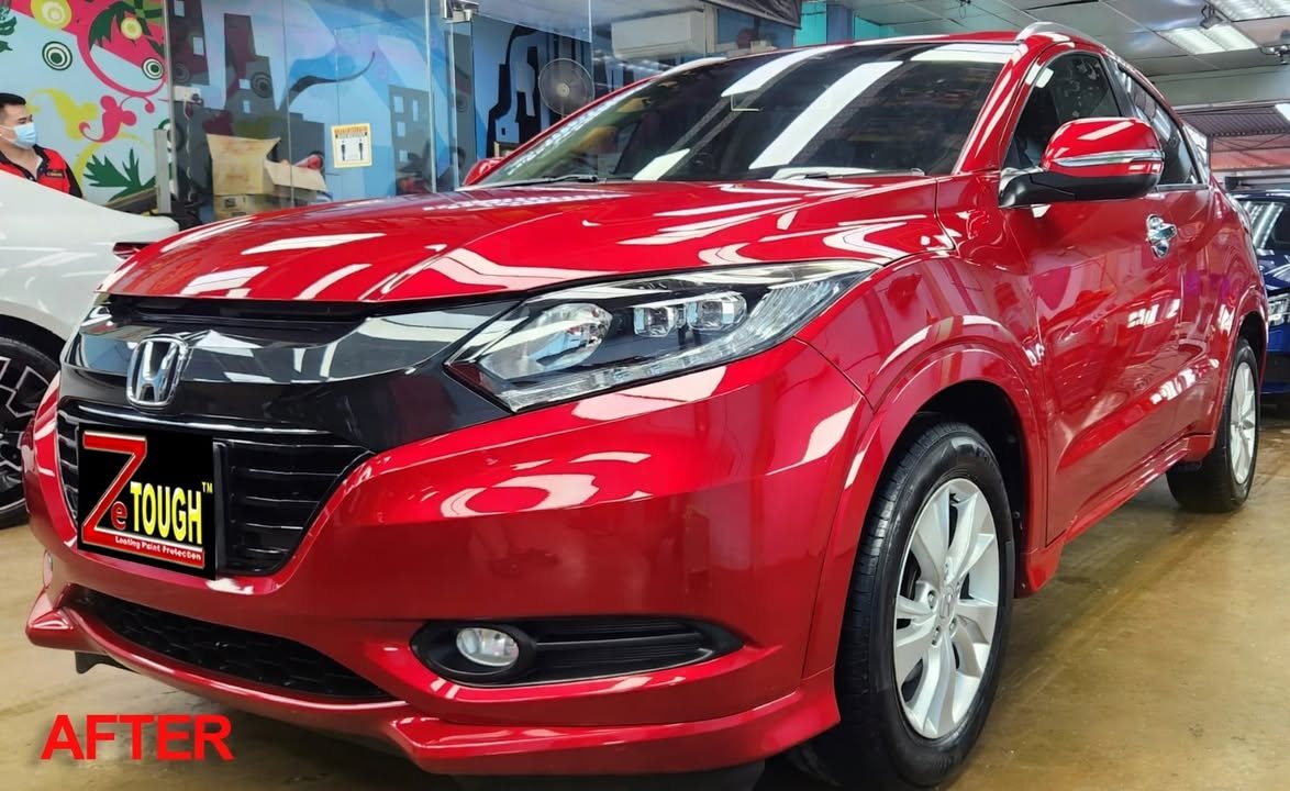 The finished red Honda HR-V from the front three-quarter, glossy paint in the workshop.