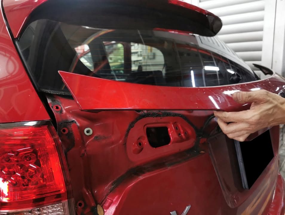 Technician removing the tailgate trim from the red HR-V.