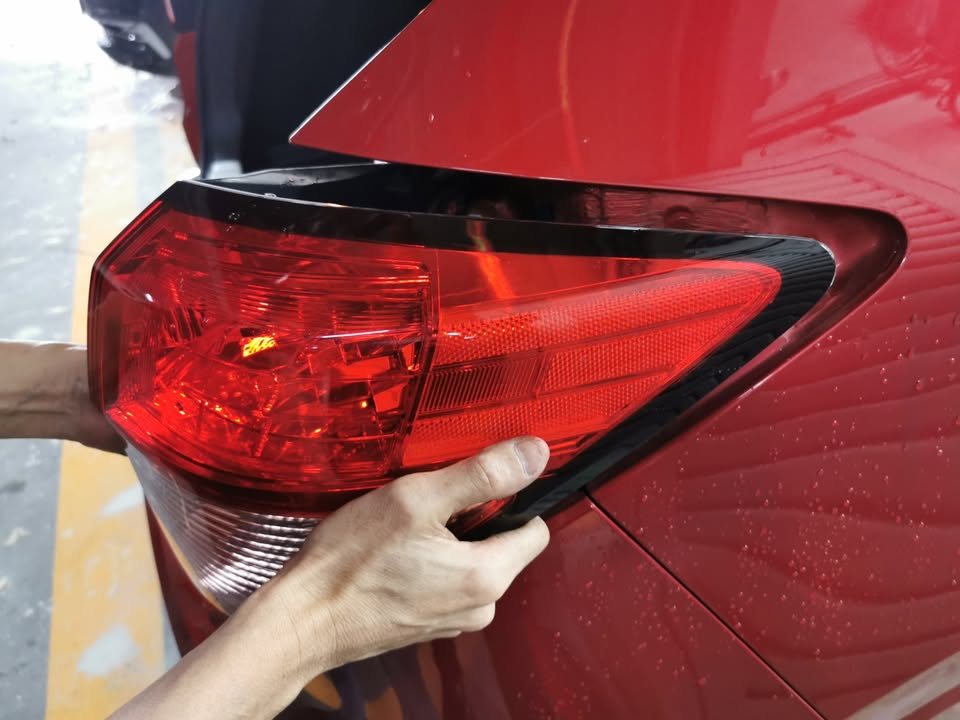 Tail lamp being taken off the red HR-V's rear quarter.