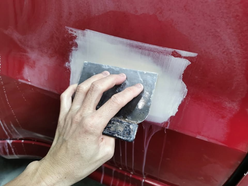 Wet sanding a primed patch on the red HR-V.