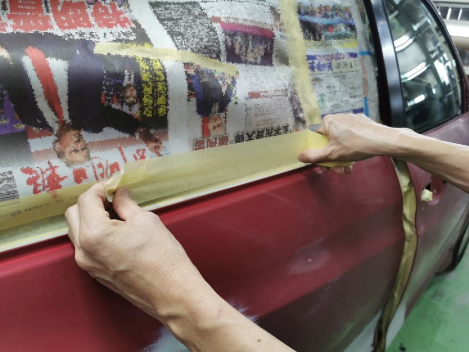 Technician masking the HR-V's window with tape and newspaper.
