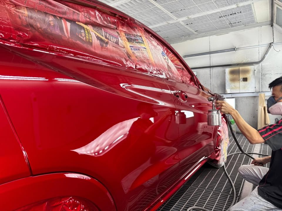 Painter spraying the side of the red HR-V in the spray booth.