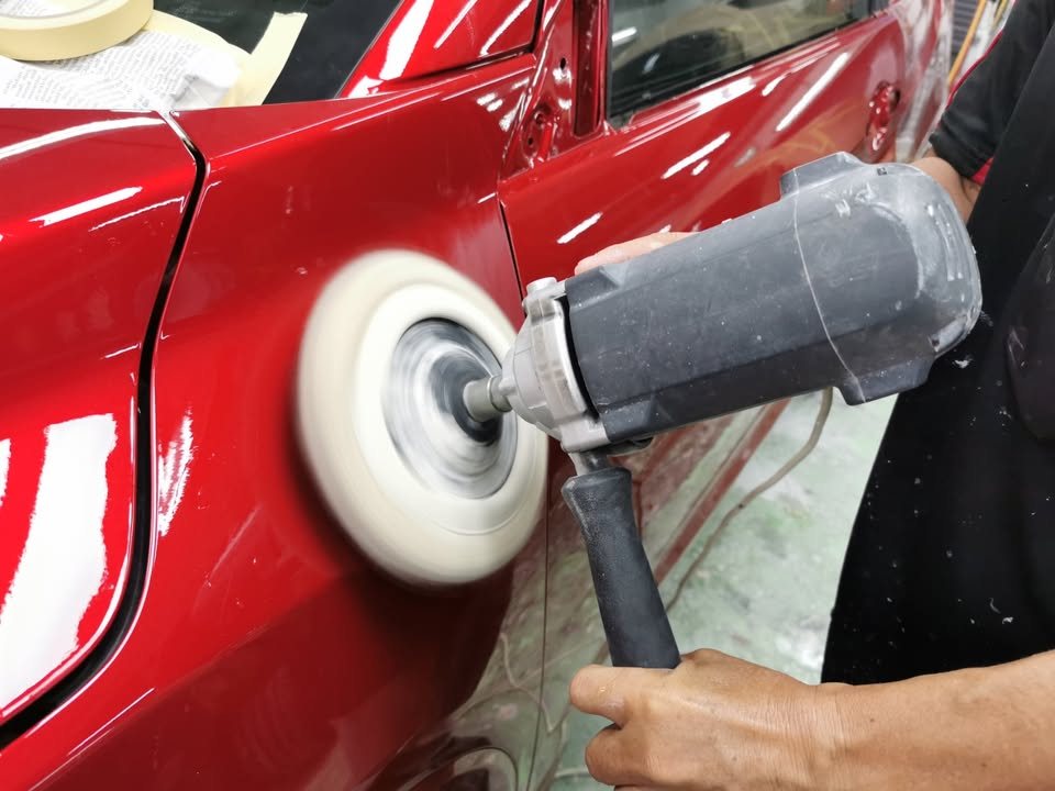 Rotary polisher with a wool pad working on the fresh red paint.