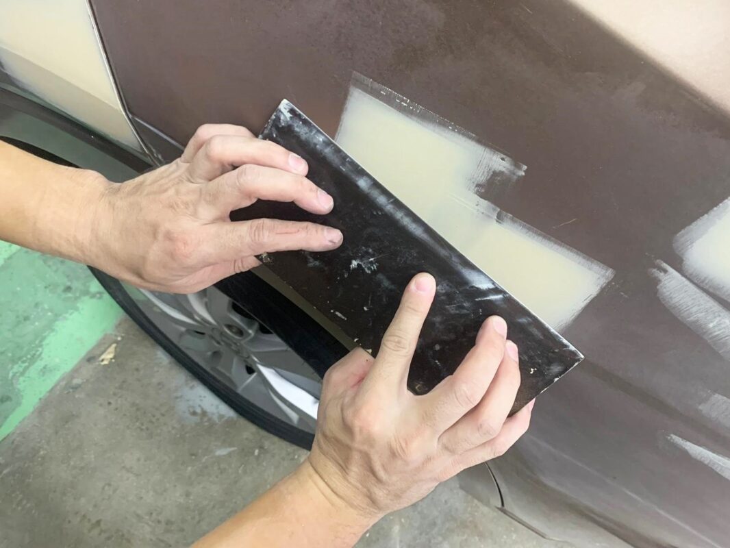 Technician examining the Honda HR-V's surface, identifying scratches and dents to repair.