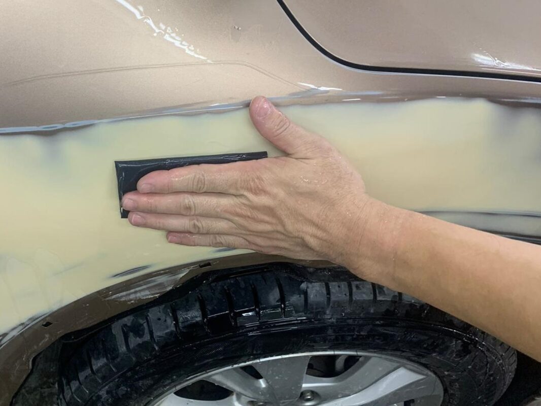 Wet-sanding a panel on the Honda HR-V to achieve a smooth, level surface.