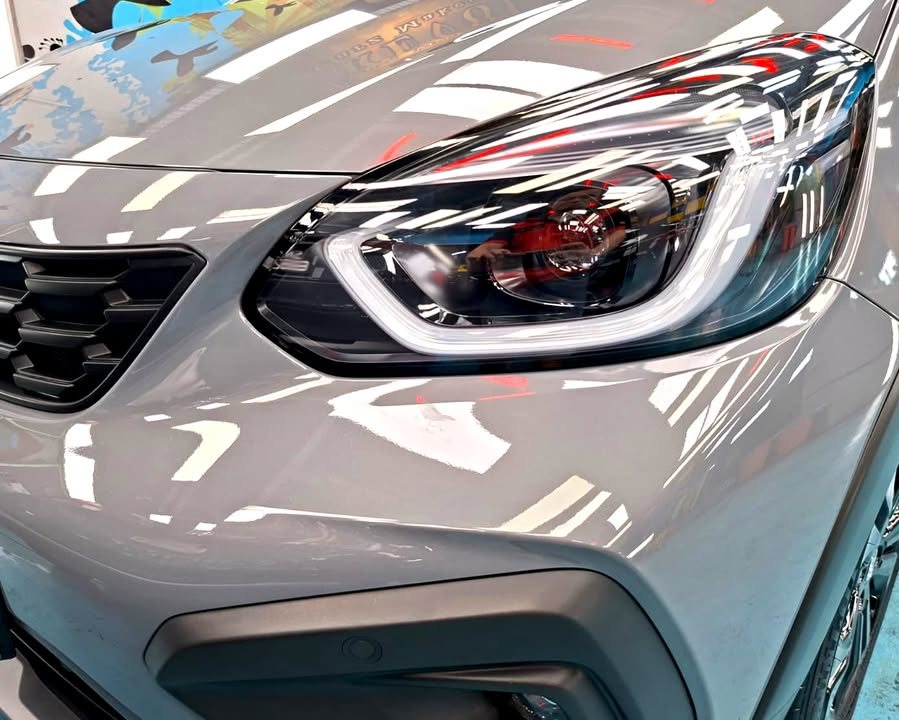 Close-up of the LED headlight and grey bonnet edge reflecting workshop lights.