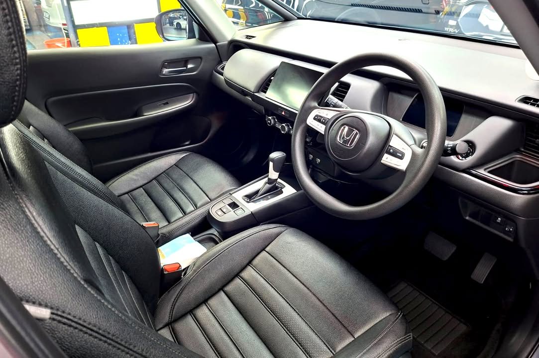 Interior with black leather seats, steering wheel and dashboard screen.