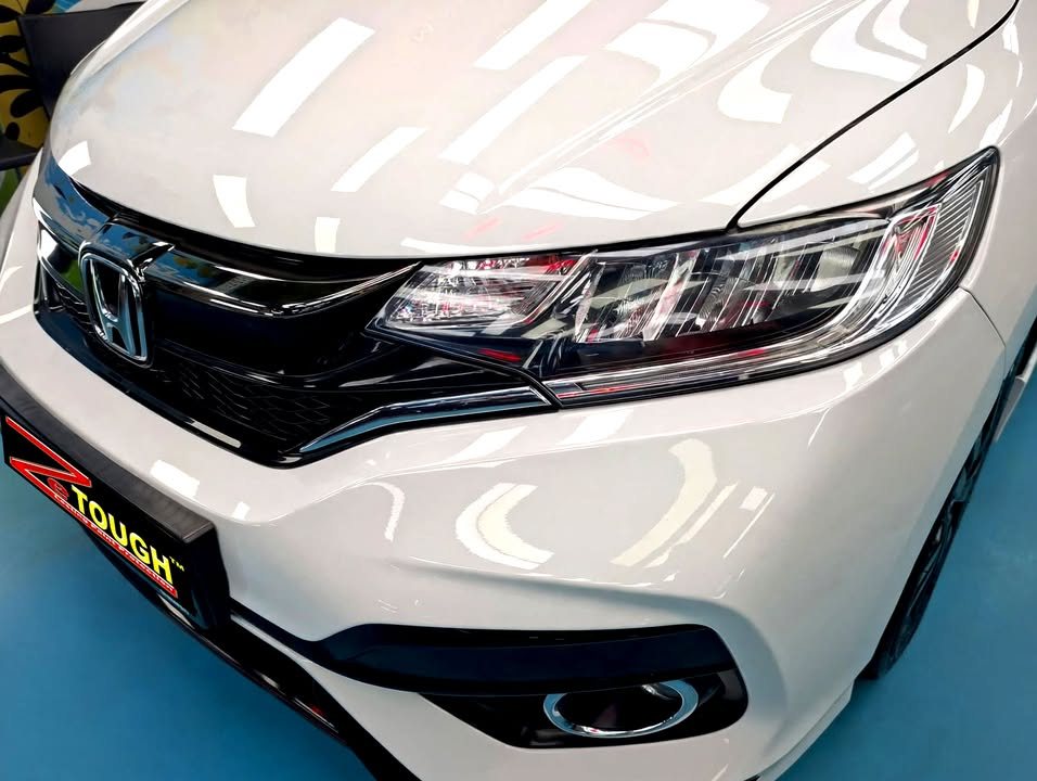Close-up of the white front bumper, grille and headlamp.