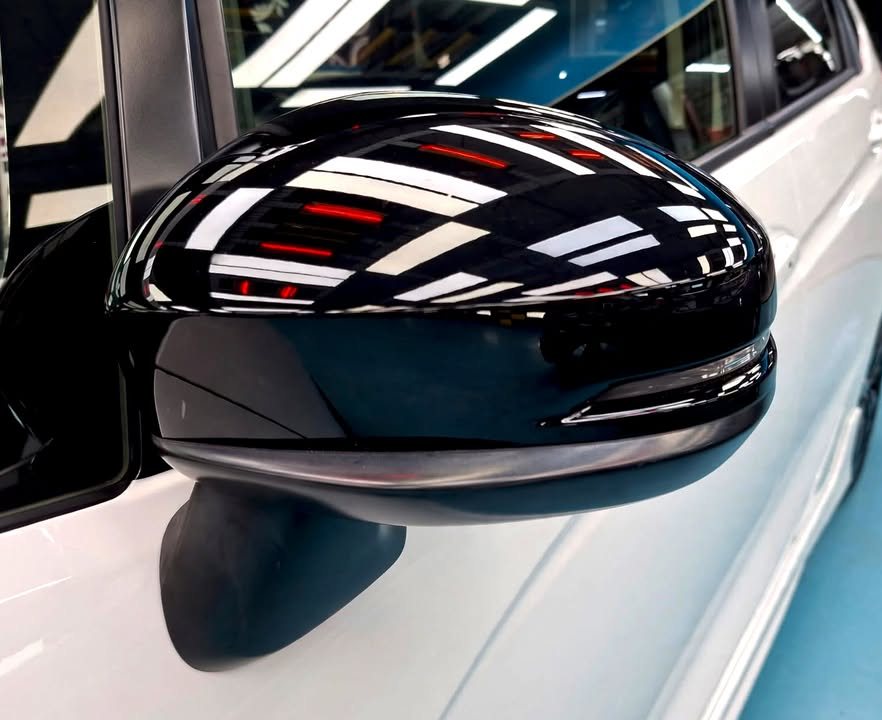 The gloss black wing mirror cap reflecting the workshop lights.