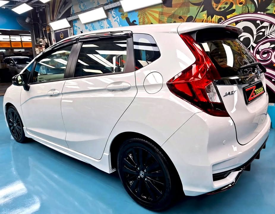 Rear three-quarter view of the white Honda Jazz with black wheels.
