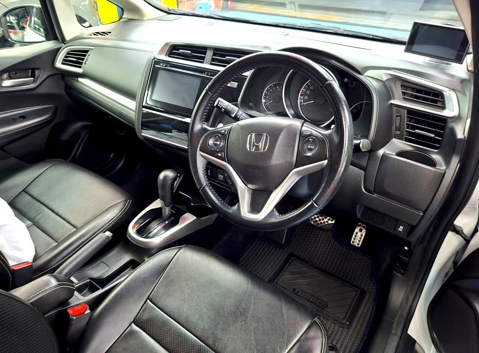 Interior view of the dashboard, steering wheel and black leather seats.