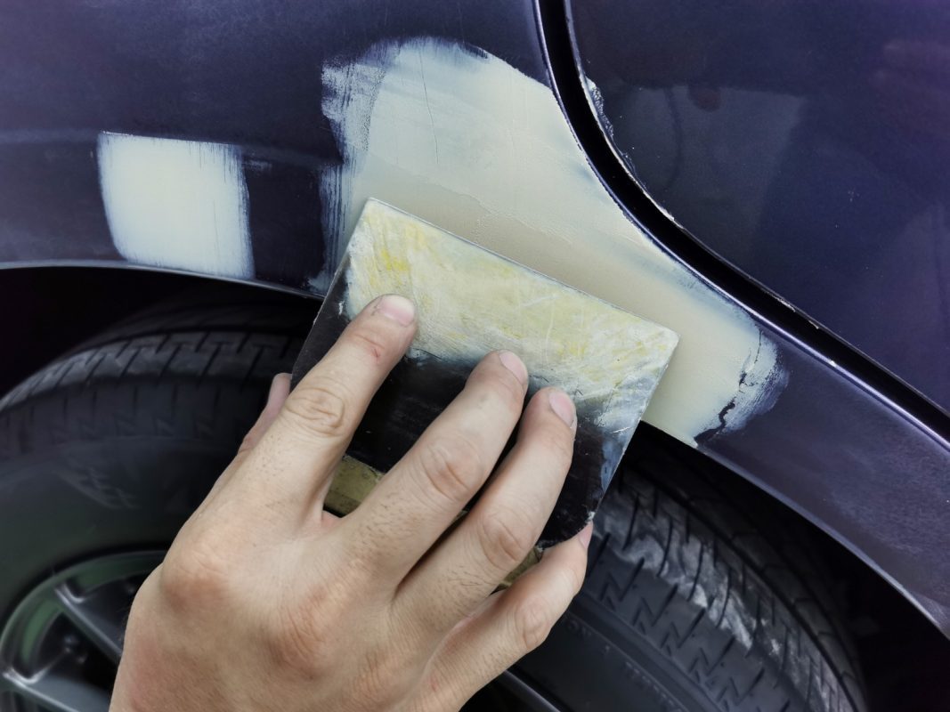 Putty being applied to even out the body surface.