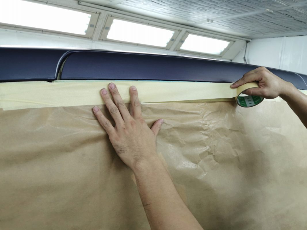 Non-painted surfaces being masked off before spraying.