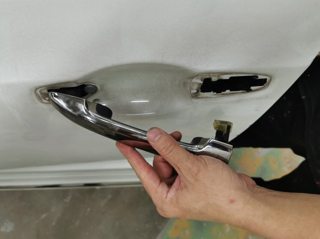 A chrome door handle removed as the Honda Odyssey is stripped down for paint.