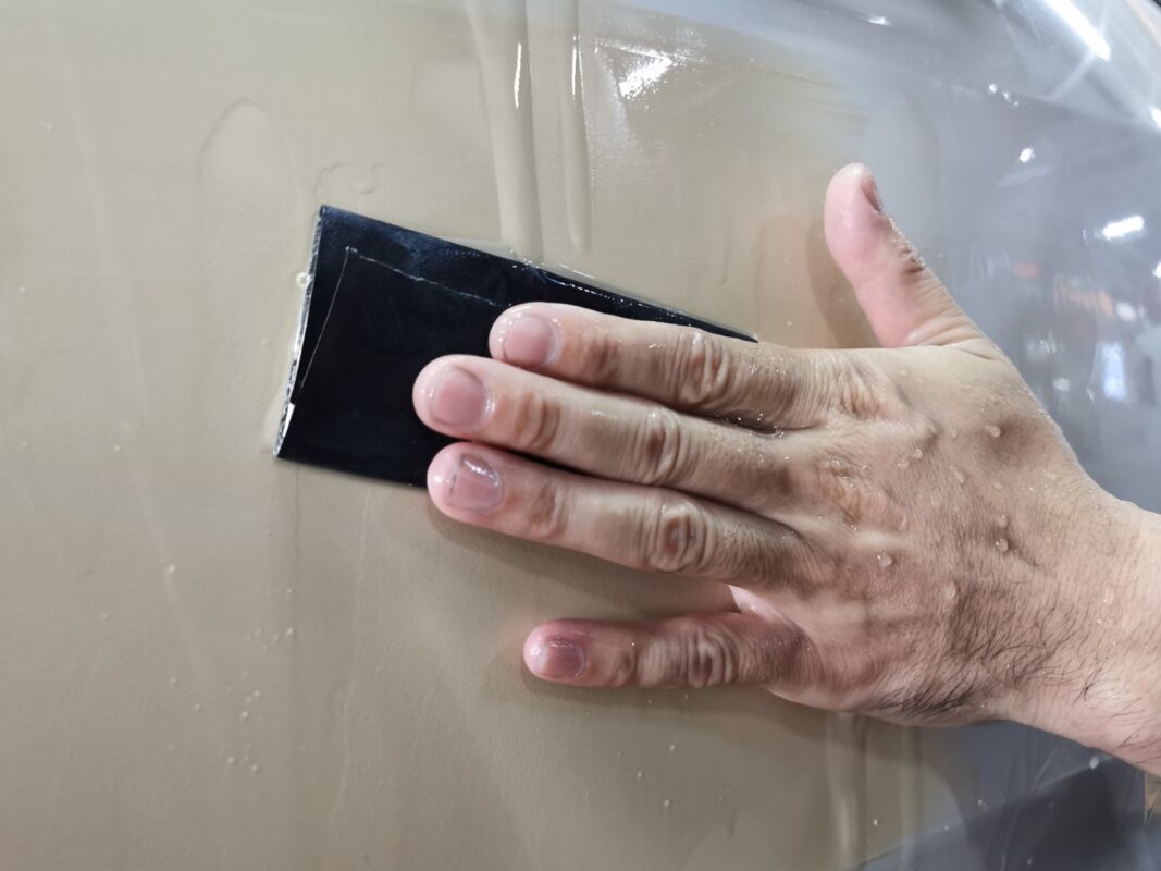 Wet-sanding a primed panel on the Honda Odyssey to a smooth surface.
