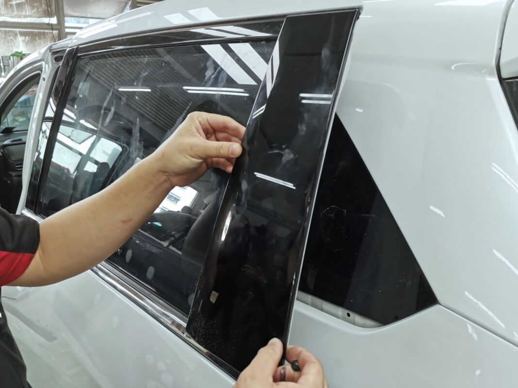 A Revol Carz painter laying the new white coat onto the Honda Odyssey in the spray booth.