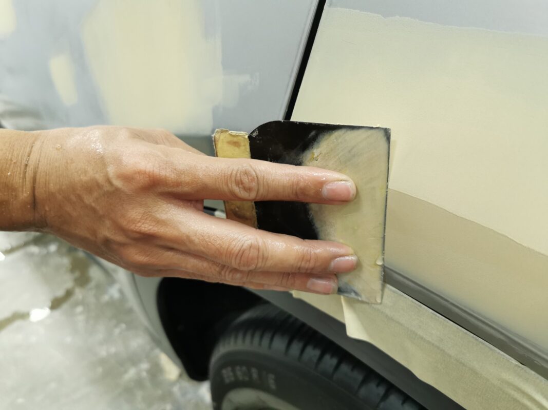 Body filler being patched on a Honda Vezel panel, surface repair in progress.