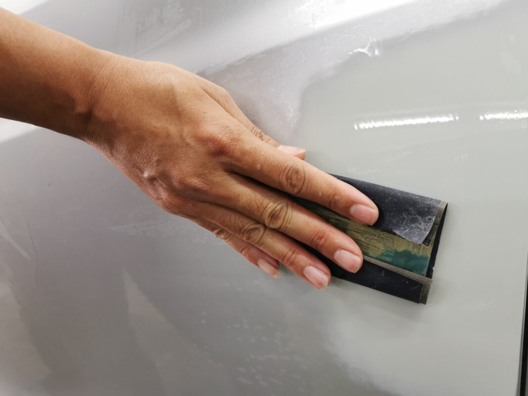 Wet-sanding a panel on the Honda Vezel to achieve a smooth, level surface.