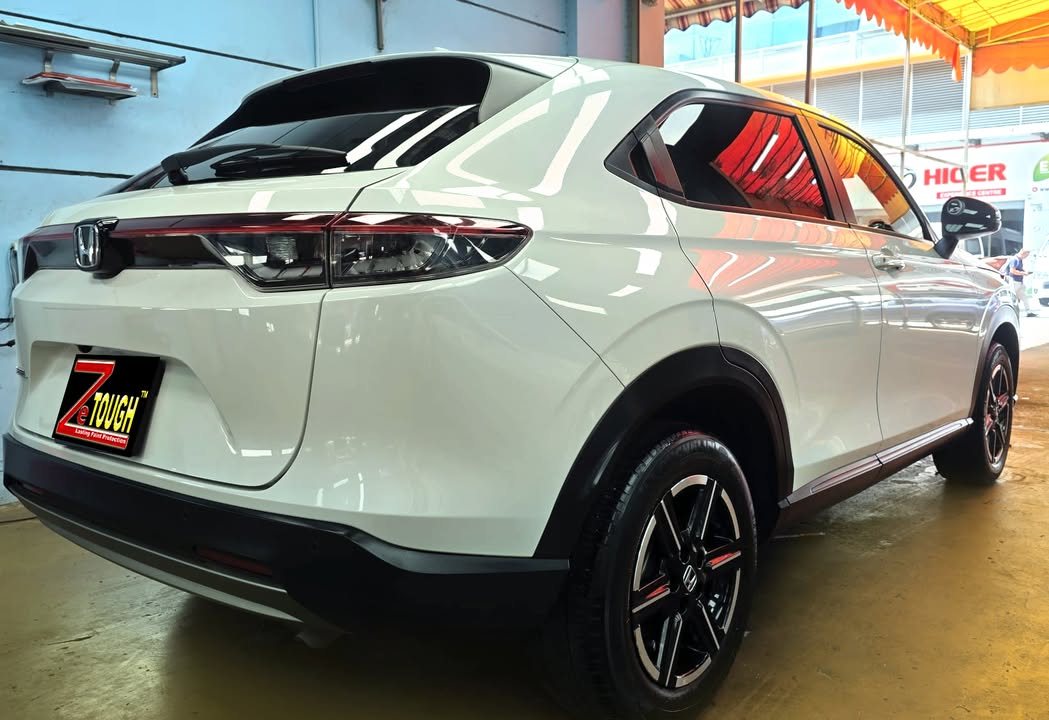Rear three-quarter view of the white Vezel with full-width tail light bar and black alloy wheels.