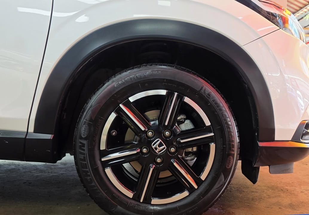 Black and silver alloy wheel with Honda centre cap under the black wheel arch trim.