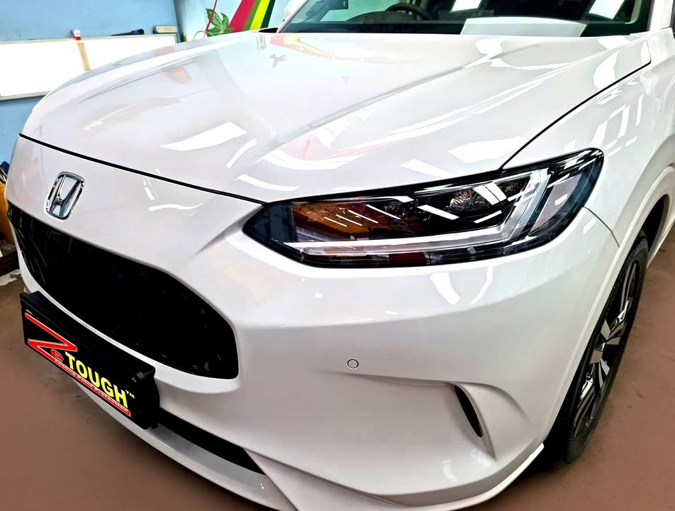Front of the white Honda ZR-V showing the grille, headlamp and bonnet.