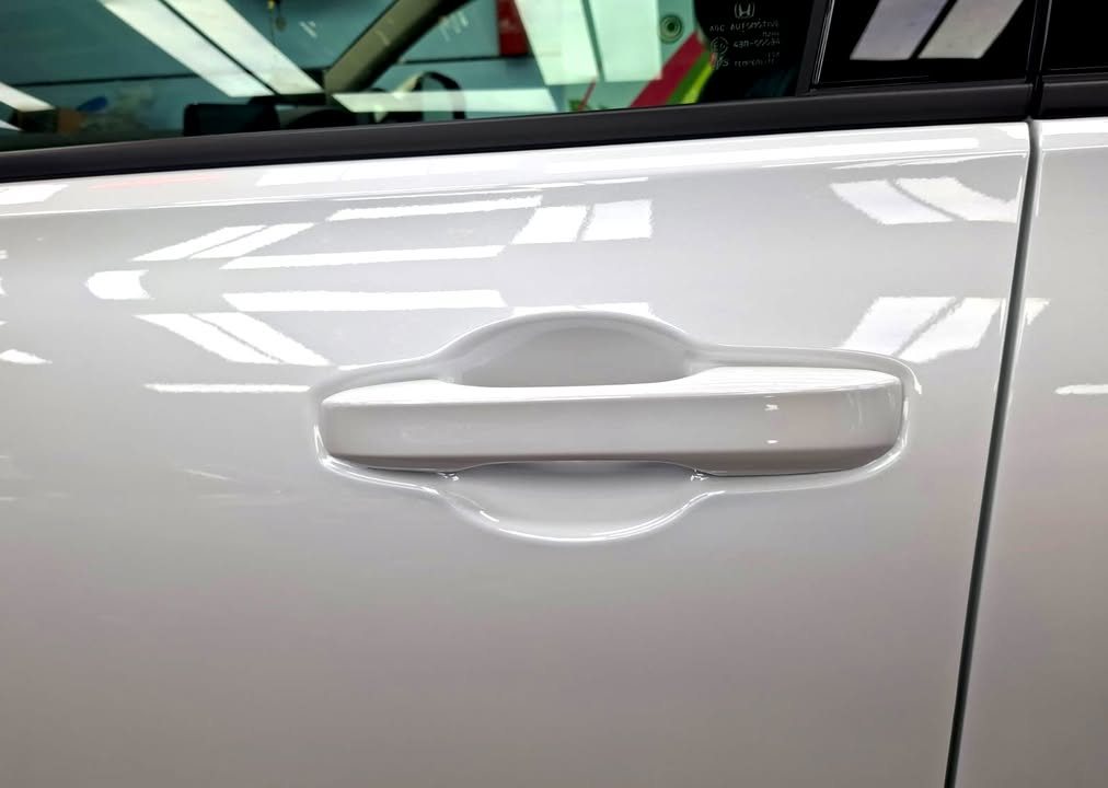 White door panel and handle on the Honda ZR-V with light reflections.