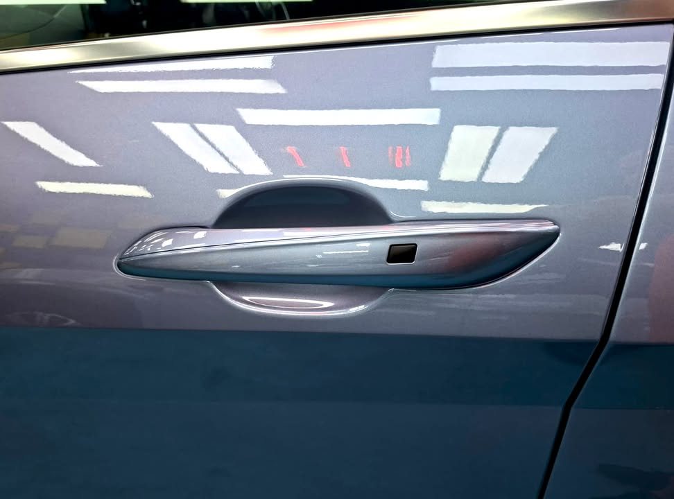 Body-coloured door handle on the blue grey door panel.