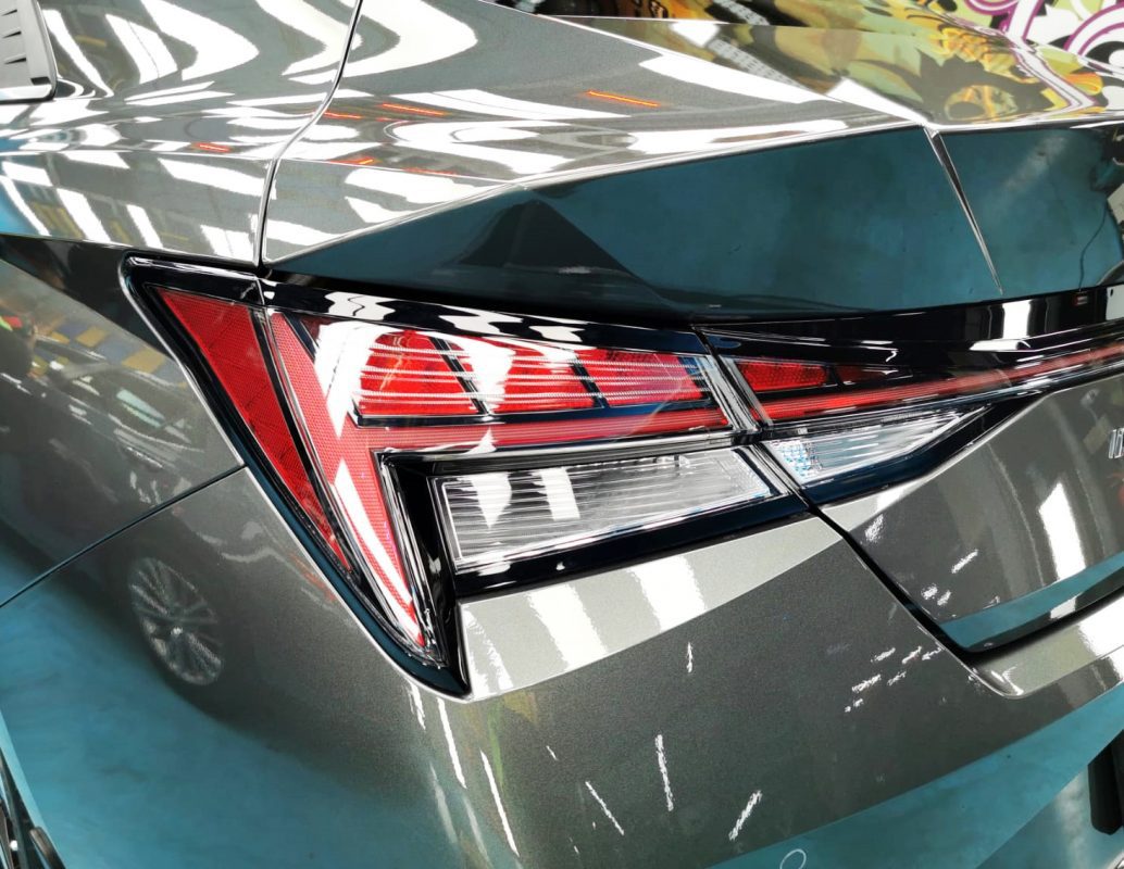 The coated bonnet of the Hyundai CN7 Avante under workshop lighting.