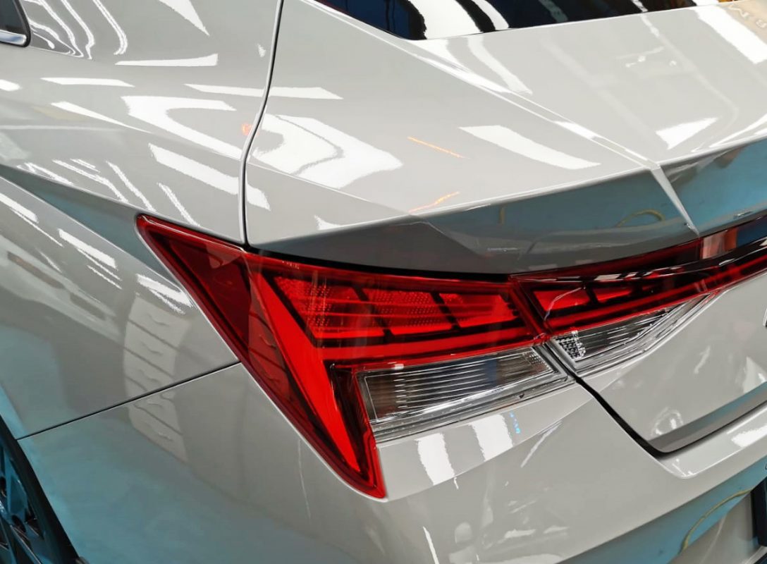 The coated bonnet of the Hyundai CN7 Avante under workshop lighting.