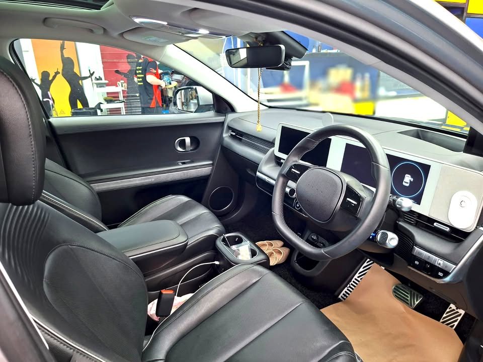 Front cabin of the Ioniq 5 with dark seats and twin dashboard screens.