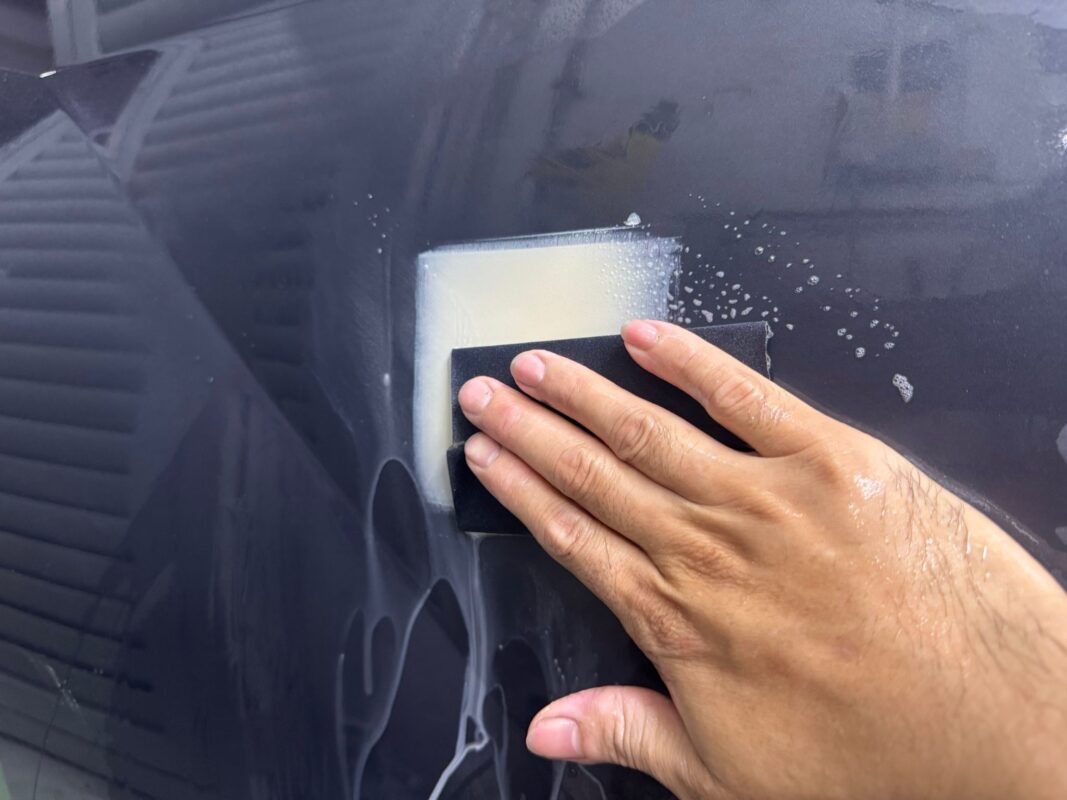 Wet-sanding a panel on the Hyundai Tucson to level the surface before priming.