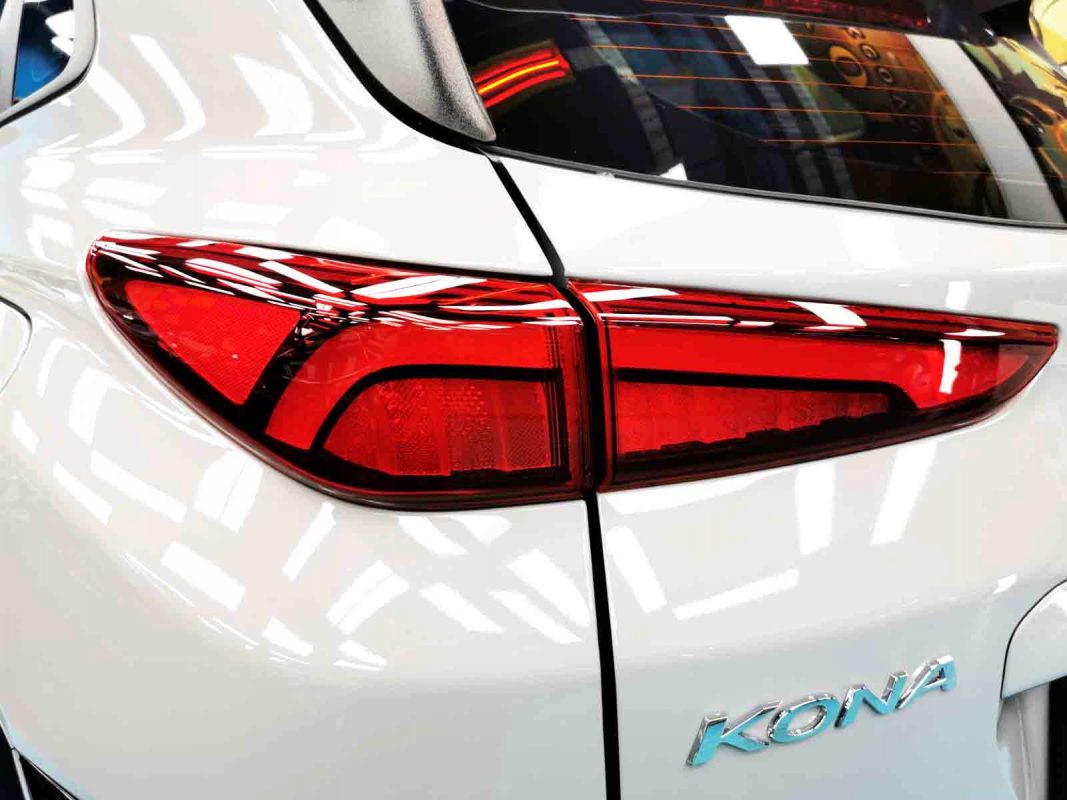 The coated bonnet of the Hyundai OS Kona HEV under workshop lighting.