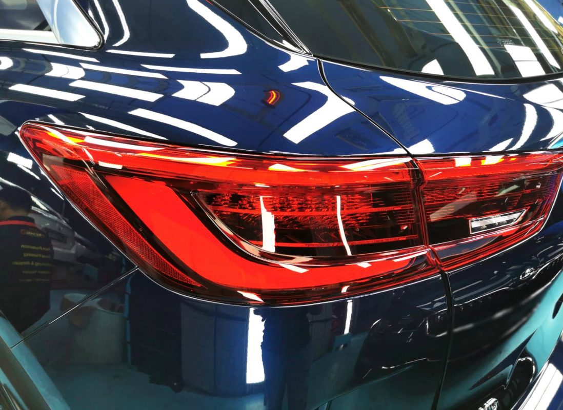 The coated bonnet of the Infiniti QX50 under workshop lighting.