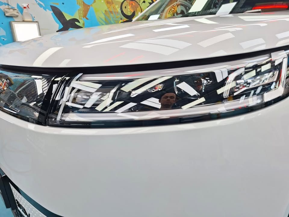 Close-up of the J5 headlight with workshop lights reflected in the white paint.