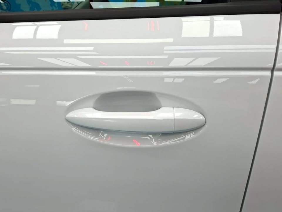 White door panel and handle of the J5 with a clear reflection.
