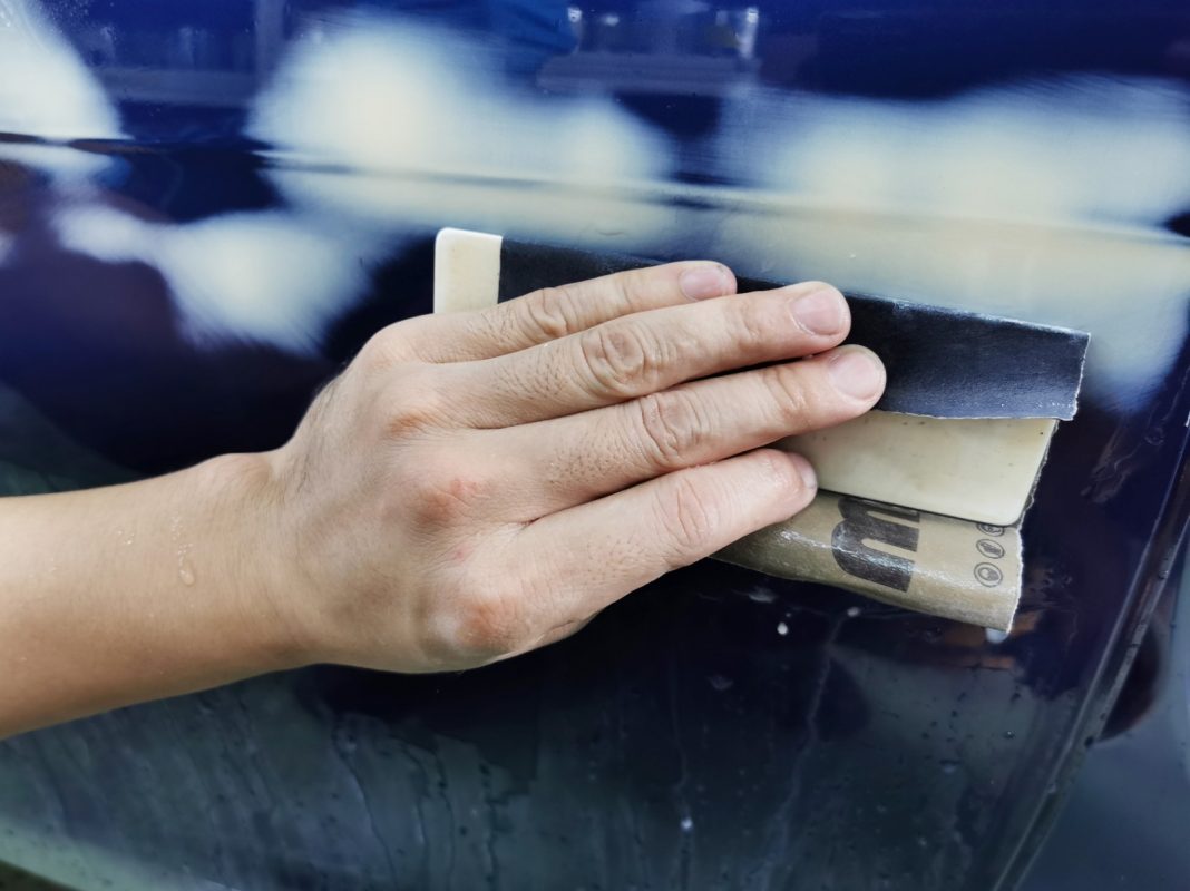 Wet-sanding the XE's panels to smooth the existing paintwork.