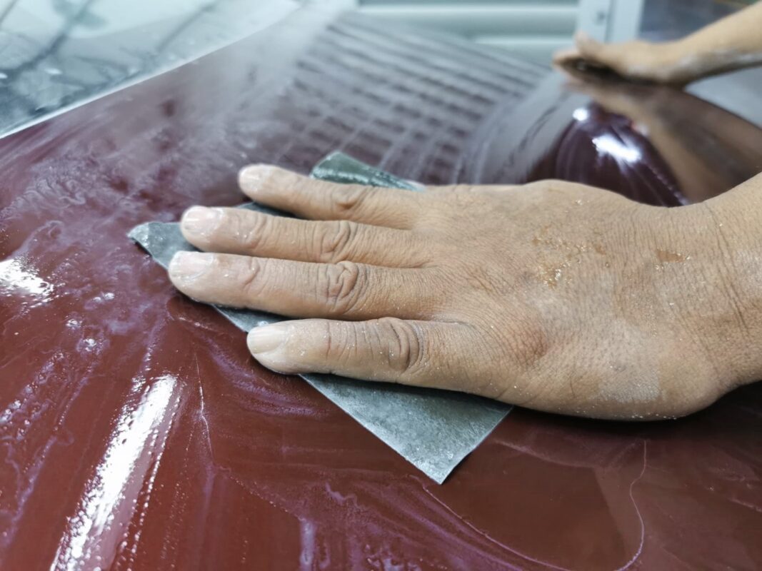 Wet-sanding a panel on the Jaguar XJ to take the surface smooth.