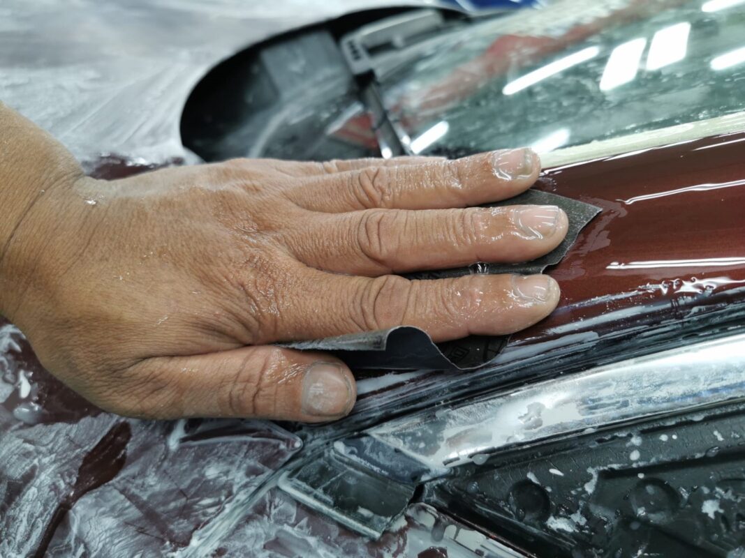 Wet-sanding the Jaguar XJ around the hood and cowl after priming.