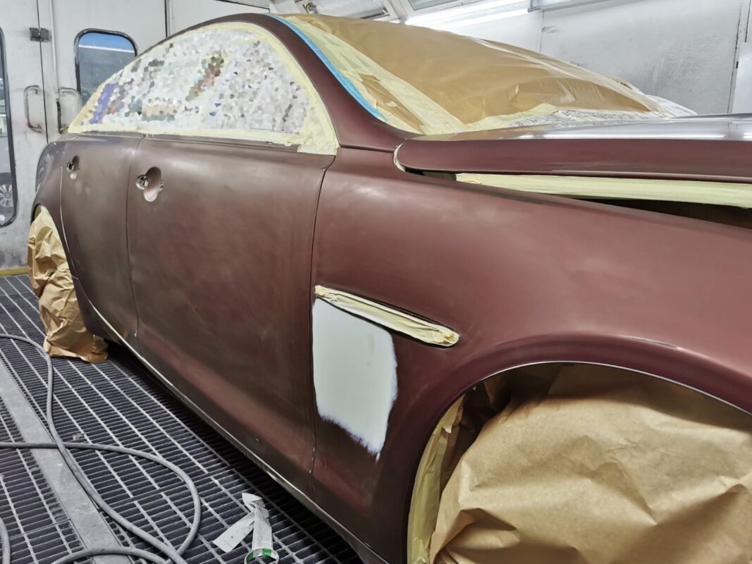 The Jaguar XJ in primer and masked up inside the spray booth.