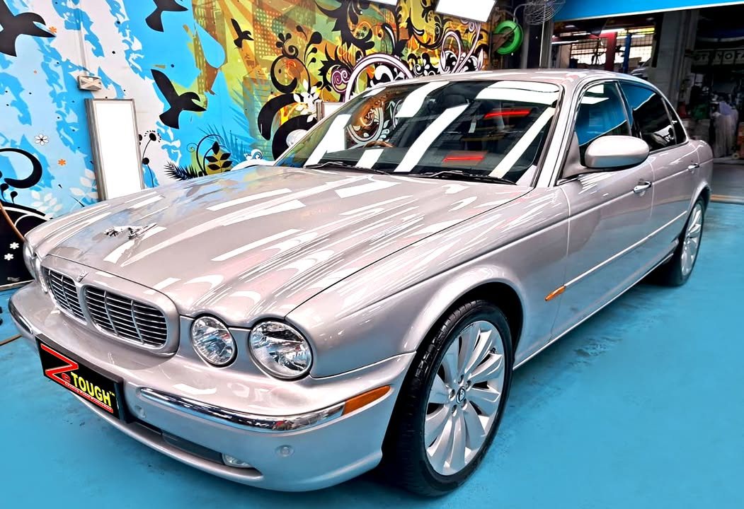 Silver Jaguar XJ8 saloon, front three-quarter view, in the Revol Carz workshop after coating.