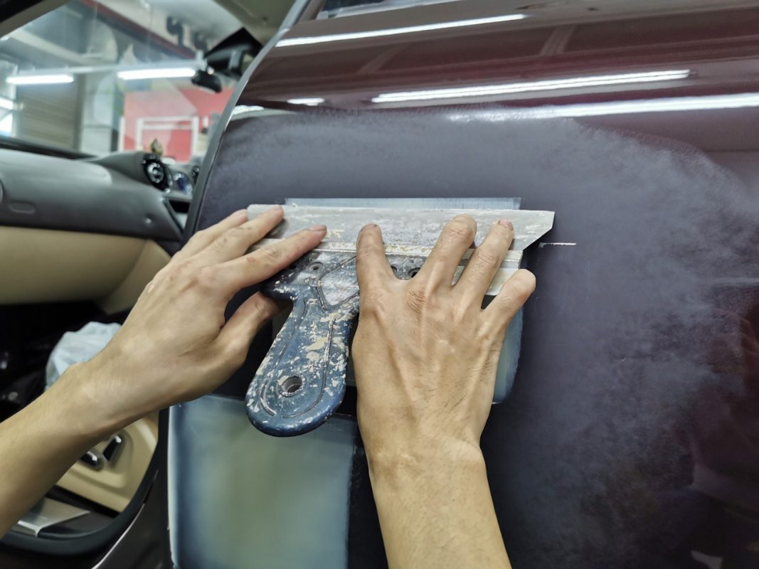 Repairing scratches and applying putty to the XJL's body.