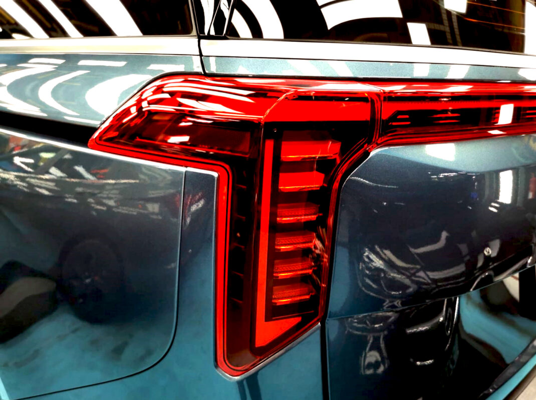 The coated bonnet of the Kia Carnival under workshop lighting.